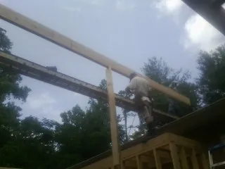 Carpenter setting a ridge beam over a new addition frame — Ice Dam Removal by Roofing Brothers in Cincinnatus