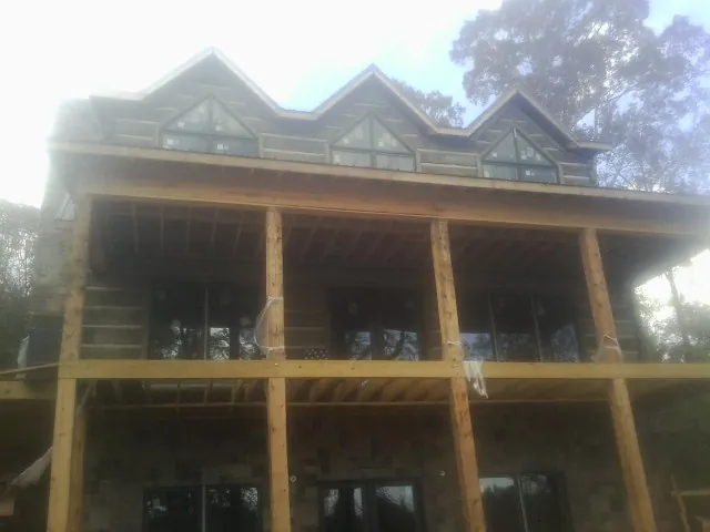 Dormers and porch framing on a large log home under construction — Roof Coating work by our crew in Cincinnatus