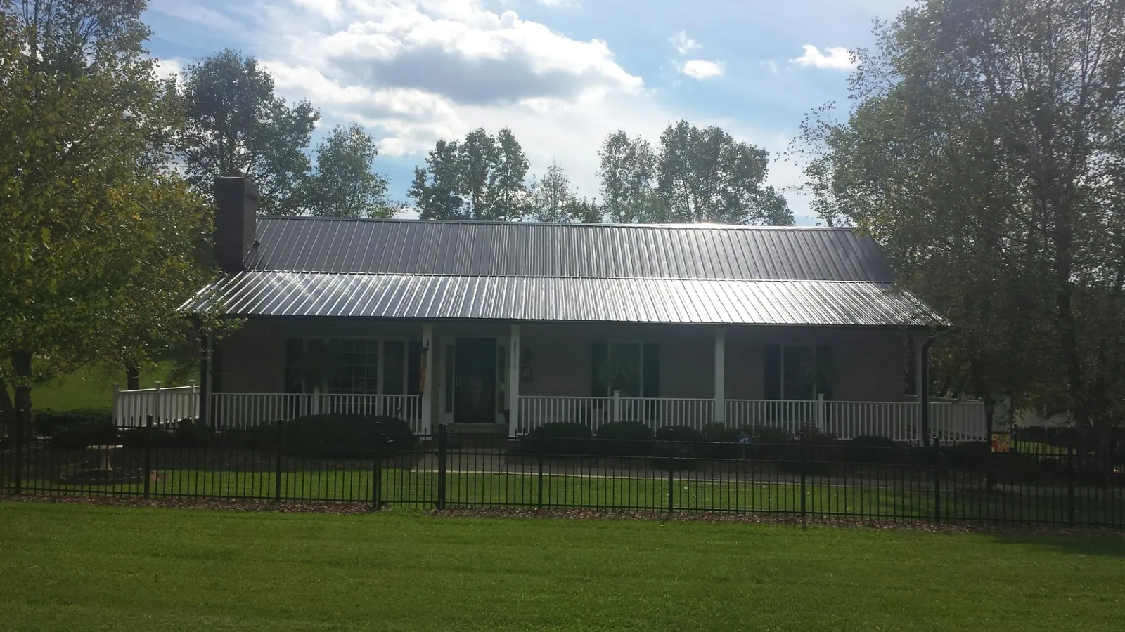 Gray metal roof on a brick ranch with a full width front porch — Gutter Guard Installation work by our crew in Cincinnatus