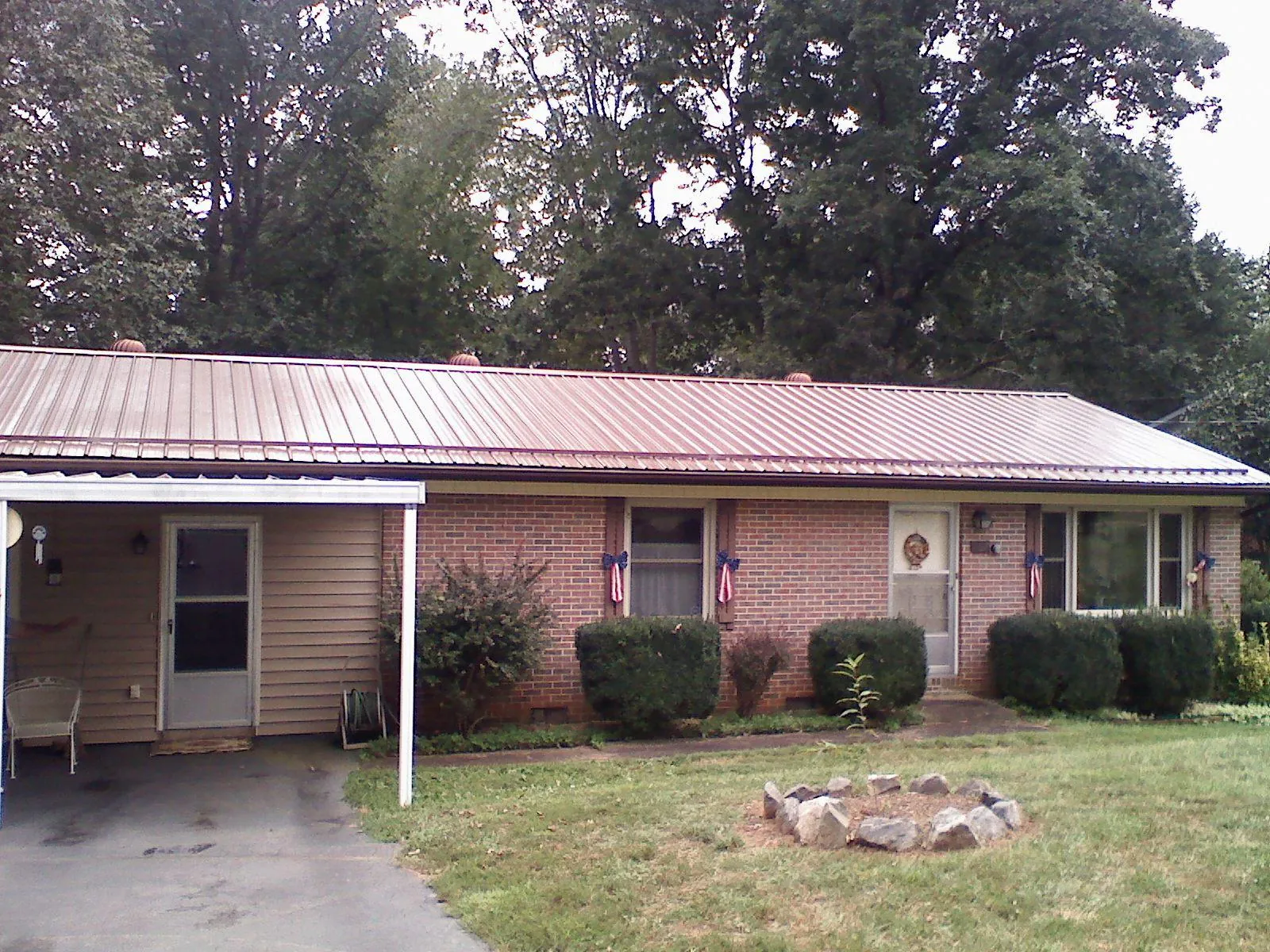 Bronze metal roof and carport on a brick ranch home — Roof Repair work by our crew in Cincinnatus