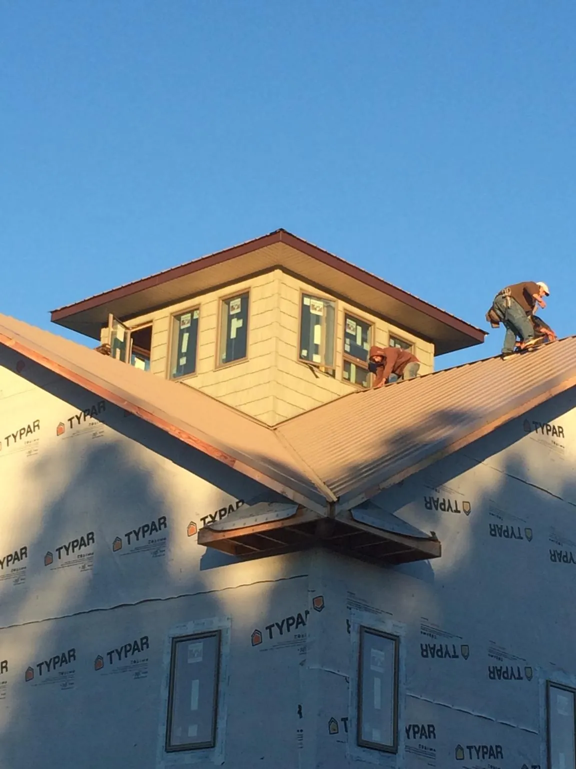 Roofers working around a rooftop cupola on a new metal roof at sunset — Roof Waterproofing in Cincinnatus by Roofing Brothers